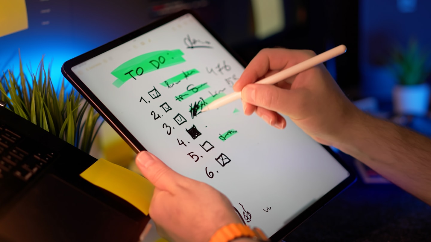 Manos usan un lápiz óptico para marcar una lista de tareas digital.