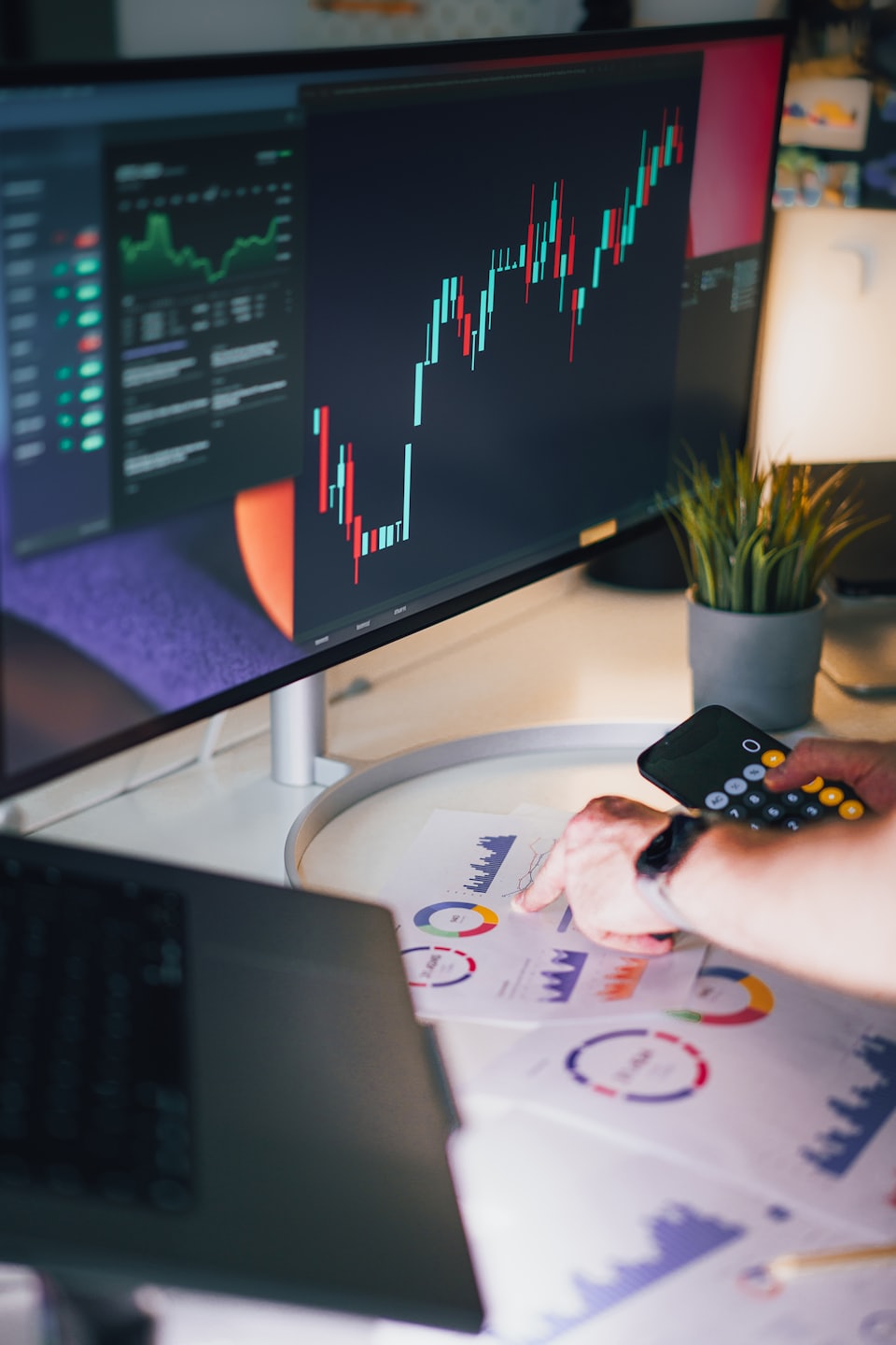 Persona analiza gráficos de datos financieros sobre un escritorio blanco.