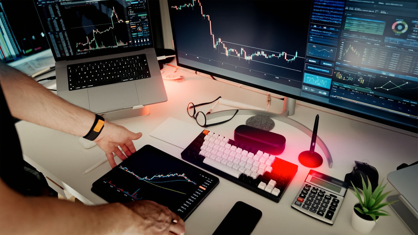 Manos usando una tablet con gráficos financieros en una oficina moderna.