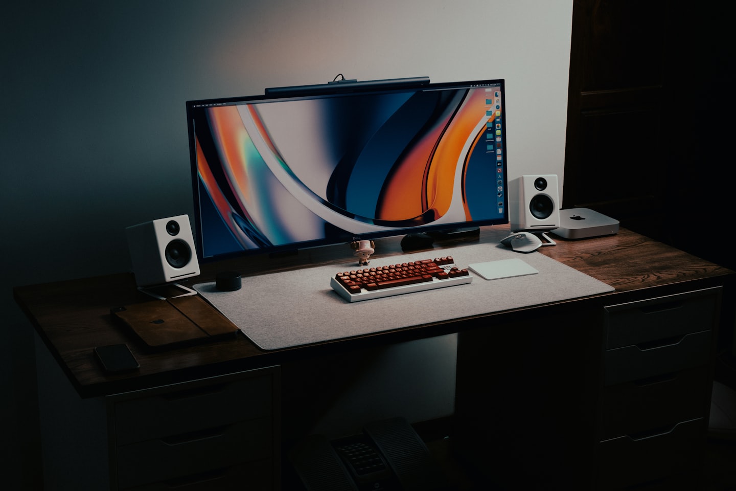 Escritorio minimalista con monitor, altavoces y periféricos sobre madera.